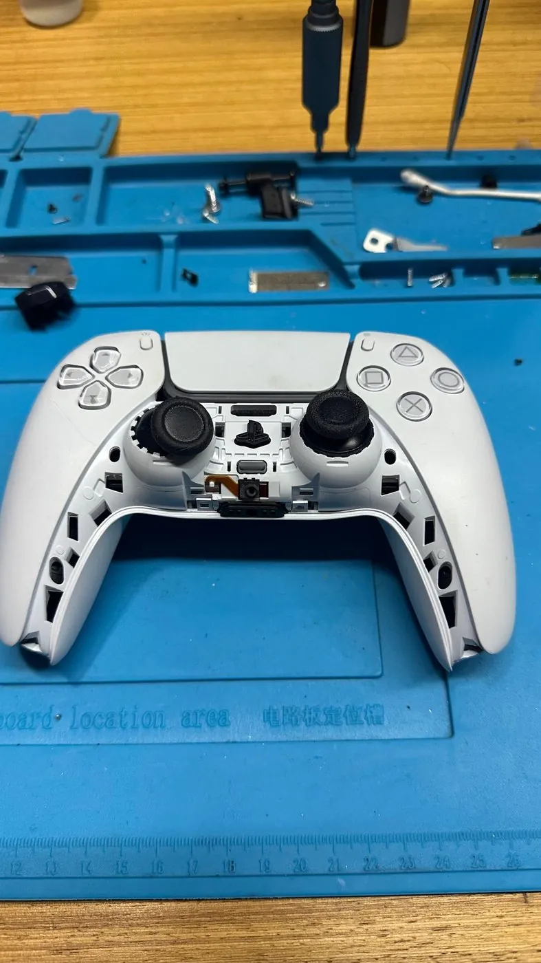 PS5 Kol Tamiri (DualSense) — Sökülmüş DualSense ön kapak ve vidalar