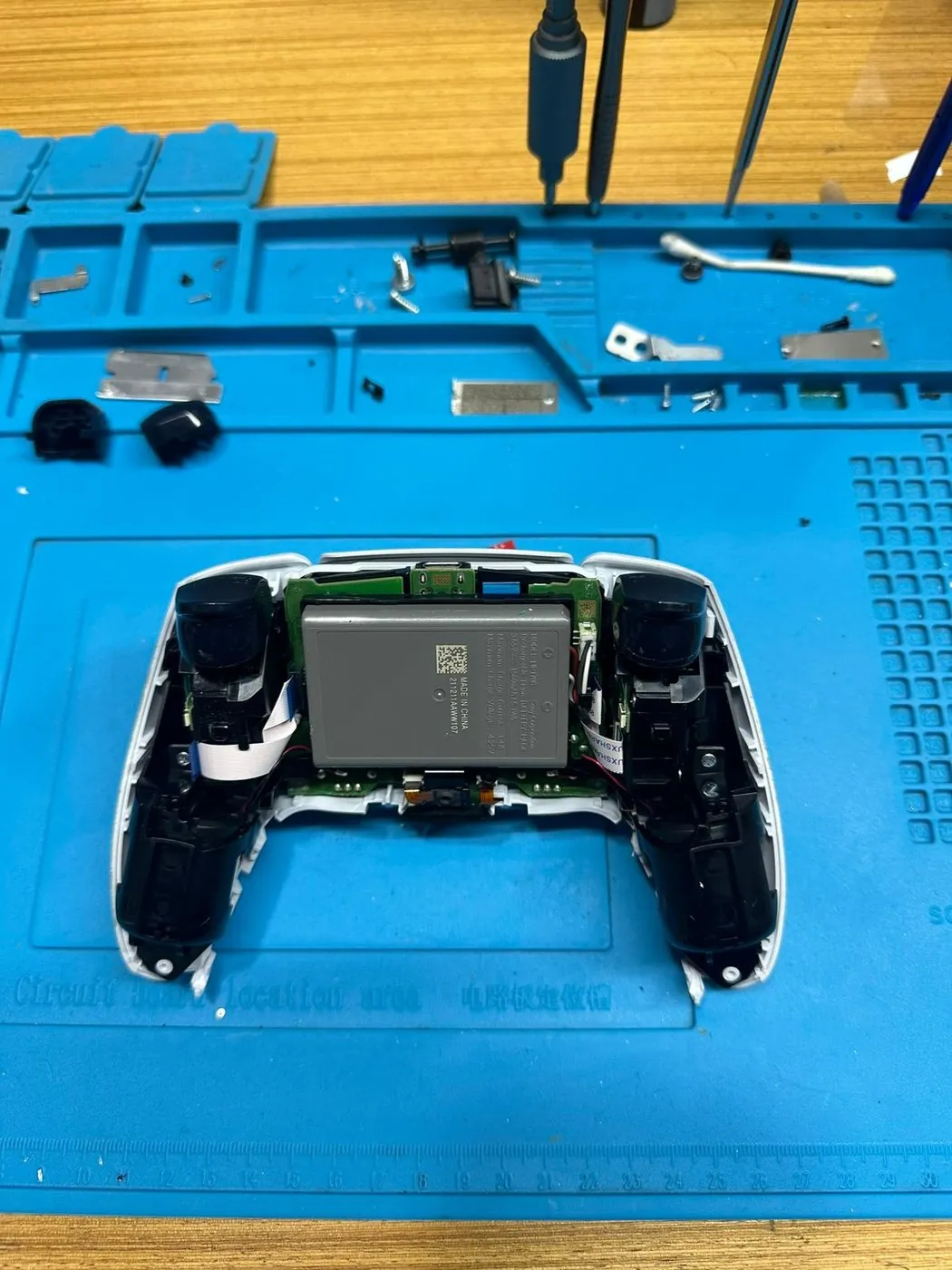 PS5 Kol Tamiri (DualSense) — Açılmış DualSense: batarya ve anakart yerleşimi